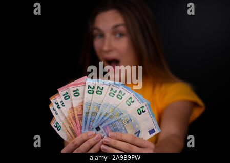 Naturali e freschi adolescente con un sacco di banconote in euro nella sua mano. Una felice espressione sul viso. Il suo primo stipendio per lo shopping? Foto Stock