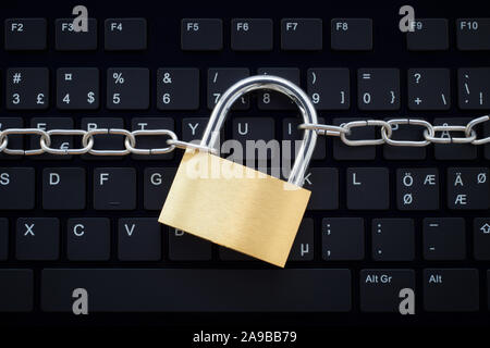 Tastiera per computer protetti da una catena di metallo e serratura. Foto il concetto di criminalità informatica e di internet e la protezione dei computer e della sicurezza. Foto Stock