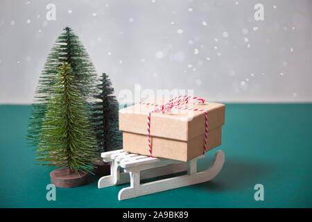 Regalo di natale Scatola sulla slitta con tre piccolo albero di Natale giocattoli. Foto Stock