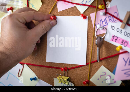 Concetto di ricerca. Vista ravvicinata di un detective board con prove. Nel centro è un vuoto mock up foglio bianco attaccato con un perno rosso. Foto Stock