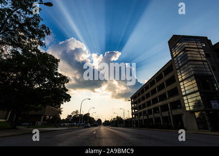 Raggi di sole che splende attraverso le nuvole in una bella giornata estiva in una città. Foto Stock