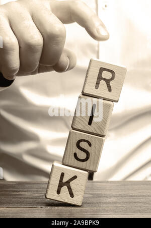 L'uomo rimuove i blocchi con la parola rischio. Il concetto di riduzione dei possibili rischi. Assicurazione, supporto di stabilità. La tutela giuridica degli interessi commerciali. F Foto Stock