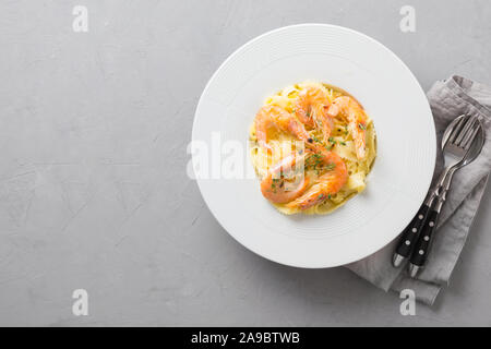 Pasta reginelle spaghetti ai frutti di mare, gamberi piastra bianca su grigio tavolo di pietra, vista da sopra. Piatto tradizionale in italiano. Spazio per il testo. Foto Stock