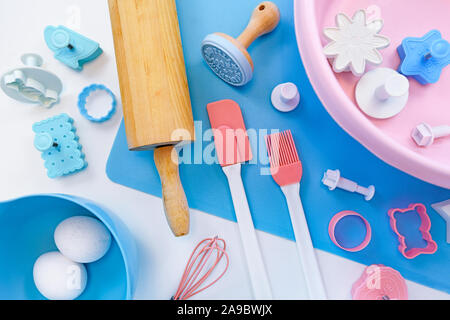 Vista superiore piatta con laici carino rosa e blu per utensili da forno come il tappeto di cottura, laminazione di legno pin, mixing bowls e cookie cutters su sfondo bianco Foto Stock