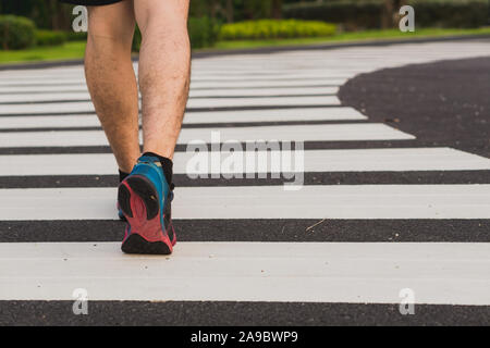 Closeup scarpa. Maschio di gambe camminando sulle strisce pedonali via. Sicurezza stradale il concetto di attraversamento Foto Stock