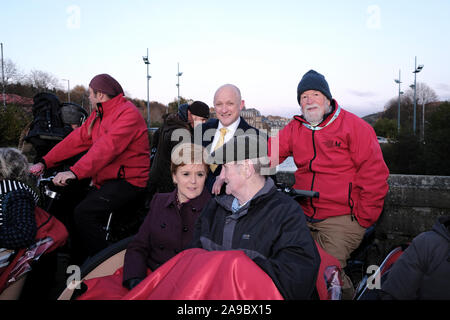 Il ponte della stazione, Hawick, UK. Xiv Nov, 2019. Nicola visite di storione Hawick incontro con i tifosi locali seduto accanto a Cirillo Corcoran (78) da Galashiels su un trio bike pilotato da Jim McPherson da Selkirk. SNP Nicola visite di storione Hawick in Scottish Borders giovedì 14 novembre 2019 e unisce il candidato locale di Calum Kerr lungo con i sostenitori in un evento pubblico sul sentiero di campagna in run fino alla elezione il 12 Dic 2019 ( Credito: Rob grigio/Alamy Live News Foto Stock