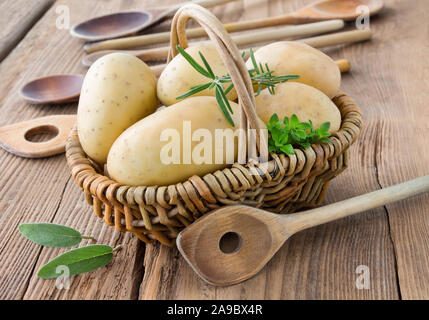 Le patate e le erbe in un cestello con cucchiai Foto Stock