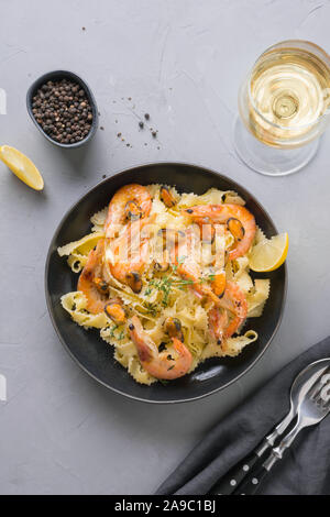 Pasta reginelle spaghetti ai frutti di mare, gamberi, cozze piastra nero su grigio tavolo di pietra, vicino. Piatto tradizionale nel ristorante italiano a Milano, R Foto Stock