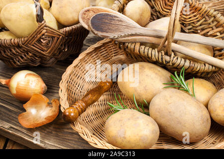 Le patate e le erbe in un cestello con cucchiai Foto Stock