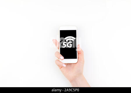 5G, rete Internet mobile ad alta velocità, reti di nuova generazione concetto. Donna mano azienda smartphone su sfondo bianco con copia spazio. Modello f Foto Stock