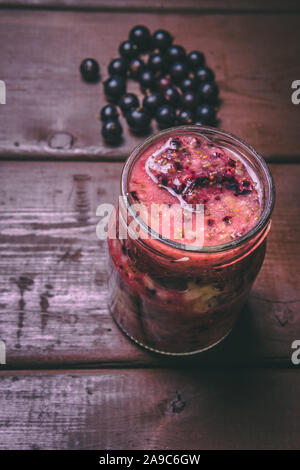 Frullati di frutta preparate con ingredienti freschi e genuini su uno sfondo di legno. Ribes nero, arancio e banana. Cibo sano concetto Foto Stock