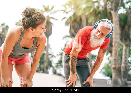 Montare la coppia di amici avente una pausa dopo una gara veloce accanto alla spiaggia al tramonto - Gli sportivi outdoor allenamento Foto Stock