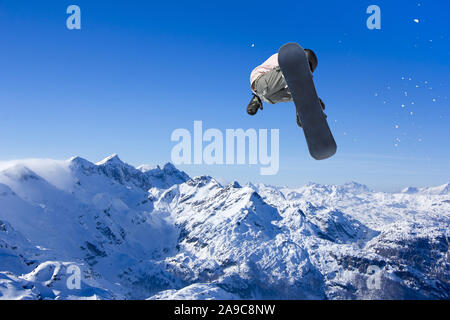 Sciatore Snowboarder jumping attraverso aria con cielo blu in background Foto Stock