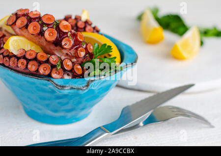 Deliziosi frutti di mare del Mediterraneo. Il polpo in una ciotola blu su sfondo bianco. Copia dello spazio. Equilibrata dieta alimentare. Foto Stock