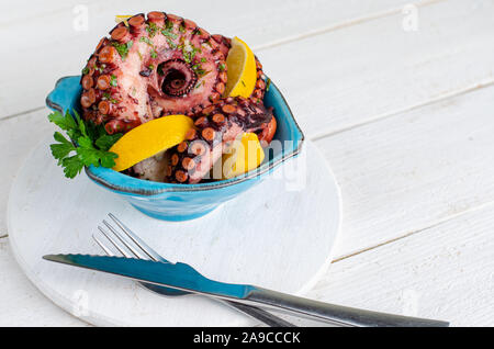 Deliziosi frutti di mare del Mediterraneo. Il polpo in una ciotola blu su sfondo bianco. Copia dello spazio. Equilibrata dieta alimentare. Foto Stock