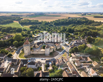 Castello medievale con le mura fortificate e torri e mastio nel villaggio rurale in Francia, vista aerea da fuco di rinnovata fortezza dal medio evo, scen Foto Stock