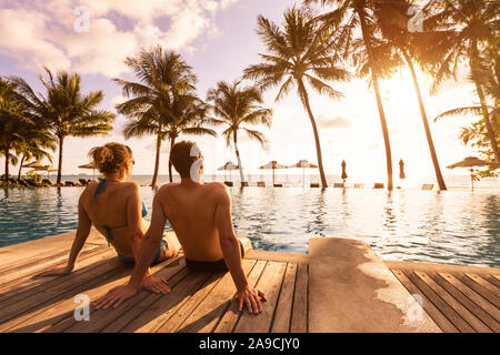 Giovane godendo spiaggia vacanza vacanze al resort tropicale con piscina e palme di cocco vicino alla costa con bellissimo panorama al tramonto Foto Stock