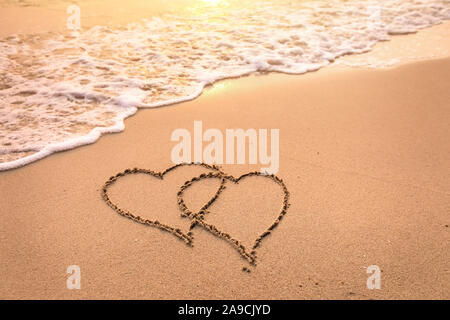 Luna di Miele romantica vacanza o il giorno di San Valentino sul concetto di spiaggia con due Cuori attirato sulla sabbia, rifugio tropicale per le coppie, simbolo di amore Foto Stock