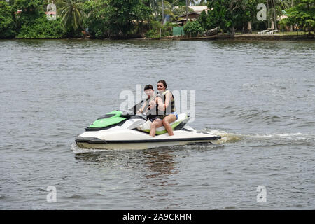 Felice coppia giovane con il pollice in alto godendo e divertirsi a cavallo su un jet ski. Costa tropicale di Sri Lanka Foto Stock