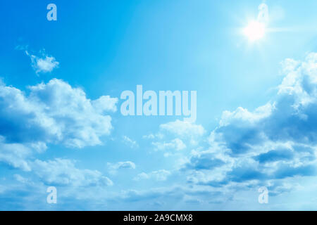 Un brillante blu cielo con sole e nuvole sullo sfondo Foto Stock