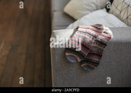 Coppia di mano Calze a maglia sul divano in interni moderni. Colori naturali. Foto Stock