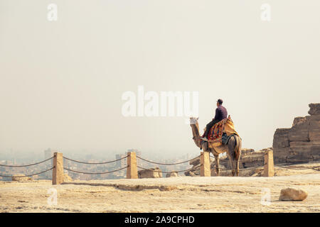 Una immagine di un giovane uomo seduto su un cammello, guardando dal sito di Giza a Il Cairo con spazio per i tuoi contenuti Foto Stock