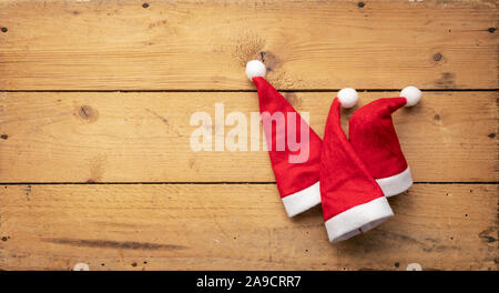 Una immagine di tre rossi Santa Claus cappelli con sfondo di legno Foto Stock