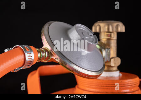 La bombola di gas e propan-butano e gas riduttore. Accessori per la casa di approvvigionamento di gas. Sfondo scuro. Foto Stock