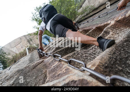 Huashan, Cina - Agosto 2019 : Tourist con zaino salire la ripida, tagliato a bordo roccioso scale su un sentiero di montagna a nord e a ovest il picco Foto Stock