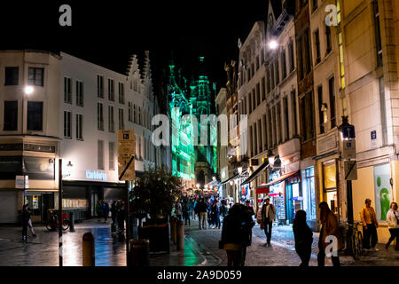 I turisti e i belgi godono di una tarda notte nel centro città come loro capo verso la Grand Place illuminato di luci verdi a Bruxelles, in Belgio Foto Stock