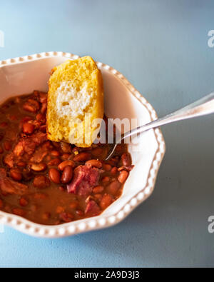 Cuocere i fagioli pinto con garretto e cornbread in una ciotola bianco. Closeup, overhead. Foto Stock