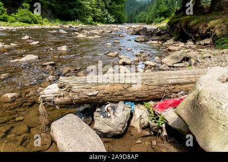 Sacchetti di plastica e bottiglie nel fiume di montagna Foto Stock