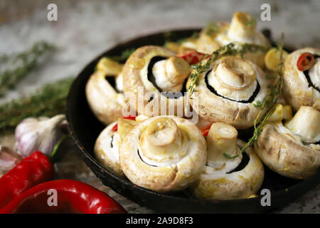 Funghi di champignon crudi grandi in una padella. Funghi in salsa prima di cuocere. Cucina vegan cibo. Champignons crudi marinati in salsa al timo Foto Stock