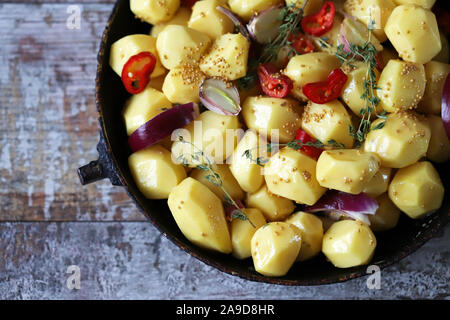 Patate sbucciate grezze intere in una padella con spezie, erbe e aglio prima di cuocere. Cottura delle patate al forno. Messa a fuoco selettiva. Macro. Foto Stock