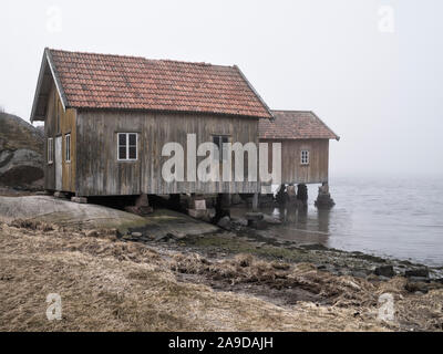 La Svezia, Bohus, West Coast, Kattegat, vecchi pescatori di cabine sulla costa vicino Hamburgsund, mare di nebbia Foto Stock