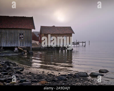 La Svezia, Bohus, West Coast, Kattegat, vecchi pescatori di cabine sulla costa vicino Hamburgsund, mare di nebbia Foto Stock