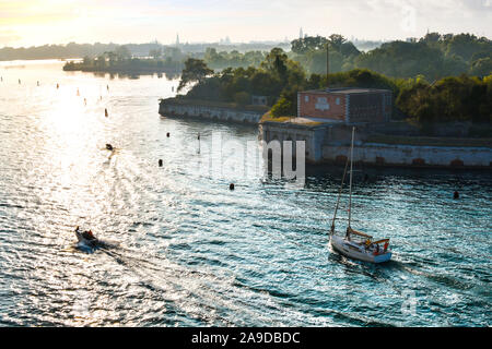 Barche di passare Forte Sant'Andrea all'isola di Le Vignole al di fuori dei principali laguna al tramonto, a Venezia, Italia Foto Stock