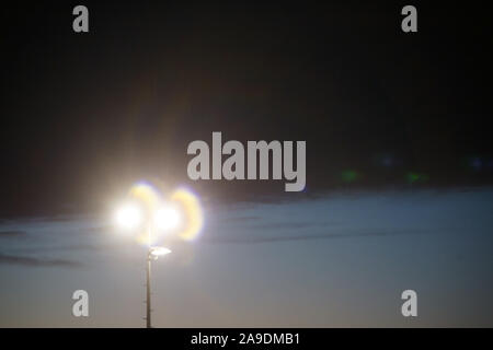 L'abstract coni di luce di un proiettore su un campo sportivo durante il tramonto. Foto Stock