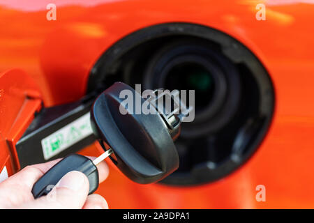 L'uomo la mano che regge il tappo del serbatoio del combustibile nella parte anteriore della benzina bocchettone di riempimento, Foto Stock