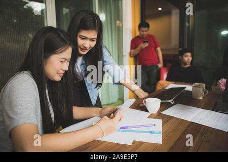 Asian giovane donna freelance a parlare con un amico di lavoro in un ufficio moderno Foto Stock