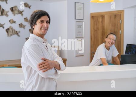 Man hotel manager in piedi vicino al front desk, donna che lavorano alla reception Foto Stock
