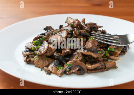 Saltata di funghi champignon con prezzemolo tritato Foto Stock