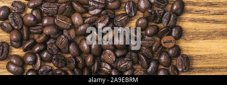 Chicco di caffè. Lo sfondo del caffè torrefatto in grani è di colore marrone su assi di legno. layout. Lay piatto Foto Stock