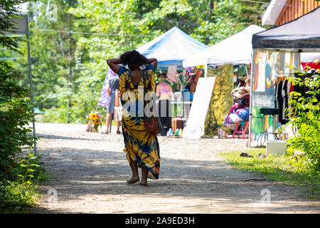 Donna africana visto dal retro indossando abiti tradizionali passeggiate tra alberi e mostre all'aperto le tende durante un appuntamento spirituale Foto Stock