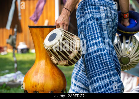 Un vicino sul uomo spirituale permanente e la holding tradizionali strumenti musicali durante un live music prestazioni pur indossando il tradizionale blu e pantaloni bianchi Foto Stock