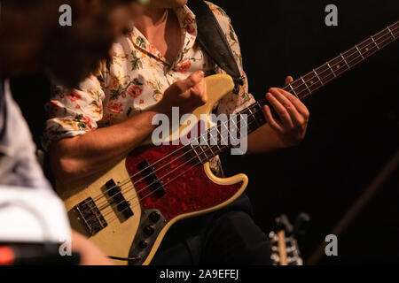 Messa a fuoco selettiva su chitarra elettrica player, il chitarrista suonando la chitarra come egli indossa camicia con fiori, con sfondo scuro e spazio di copia Foto Stock