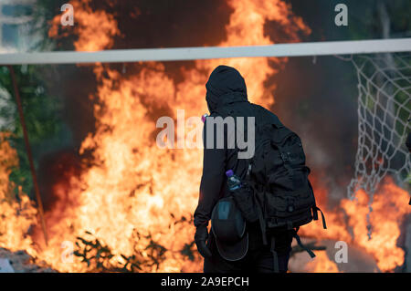 Studente passando il fuoco barricade. Un inedito battaglie all Università cinese di Hong Kong (CUHK). Hong Kong continua protesta sul suo quinto mesi. Un sciopero cittadine chiamato per iniziato lunedì 11 novembre, 2019 che ha portato le parti di Hong Kong per fermare come le stazioni MTR chiuso e più blocchi stradali sono state erette. Hong Kong, 12.11.2019 Foto Stock