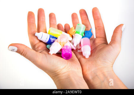 Tenendo la mano di vernice colorata di bottiglie piccole per i bambini. Immagine isolata Foto Stock