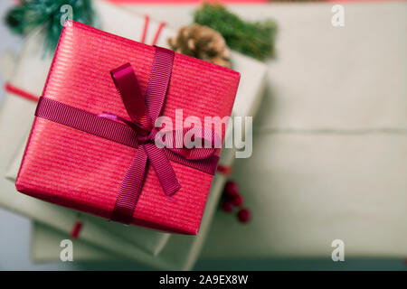 Classy regali di Natale scatola presenta sul rosso e marrone carta con nastri rossi e alcune decorazioni. Rifiuti Zero. Foto Stock