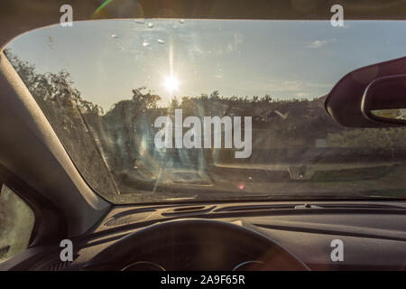 Sporco il parabrezza di un auto con striature come ostruzioni visive sotto il sole Foto Stock